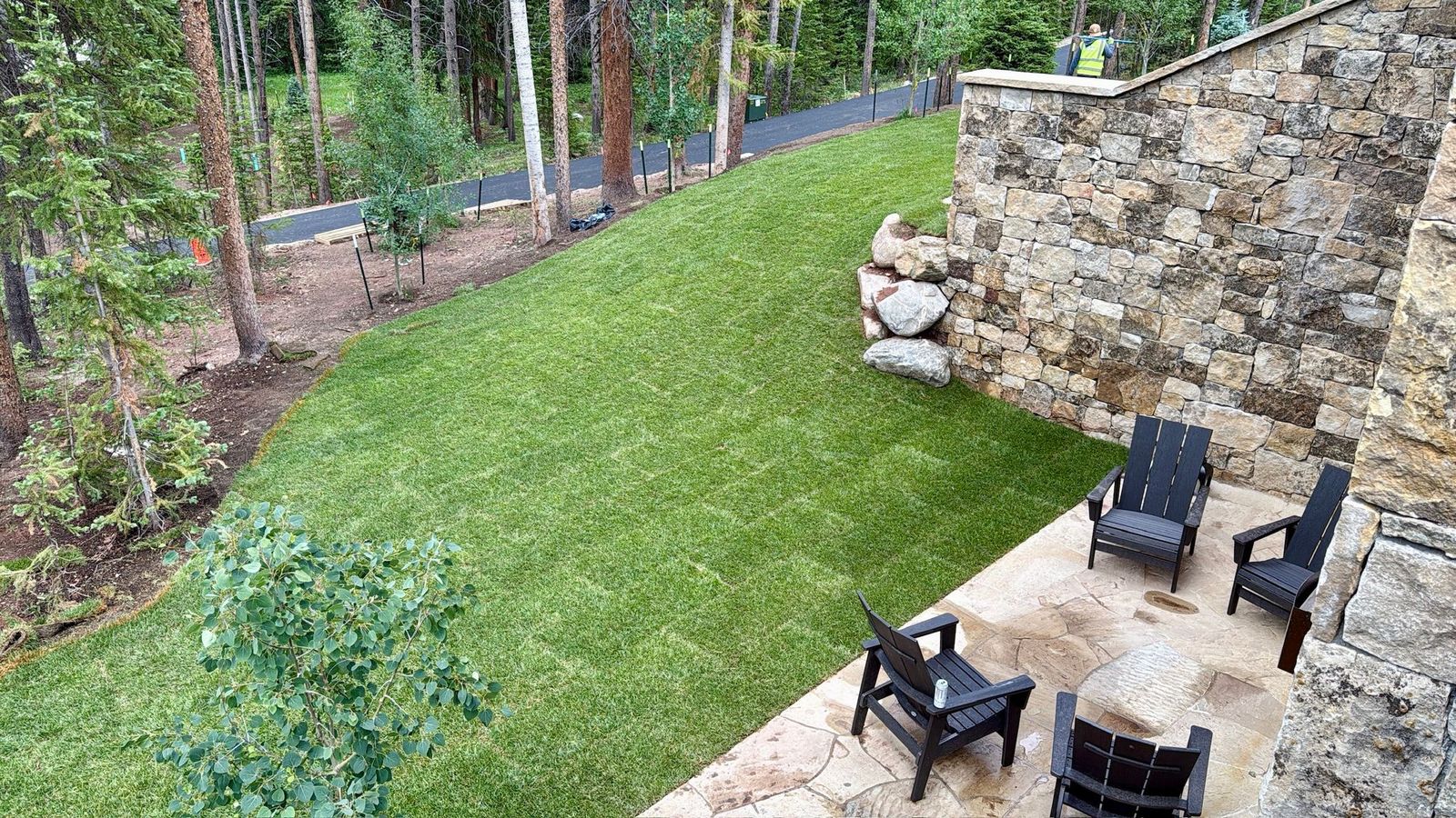 Backyard lawn with stone retaining wall and patio seating